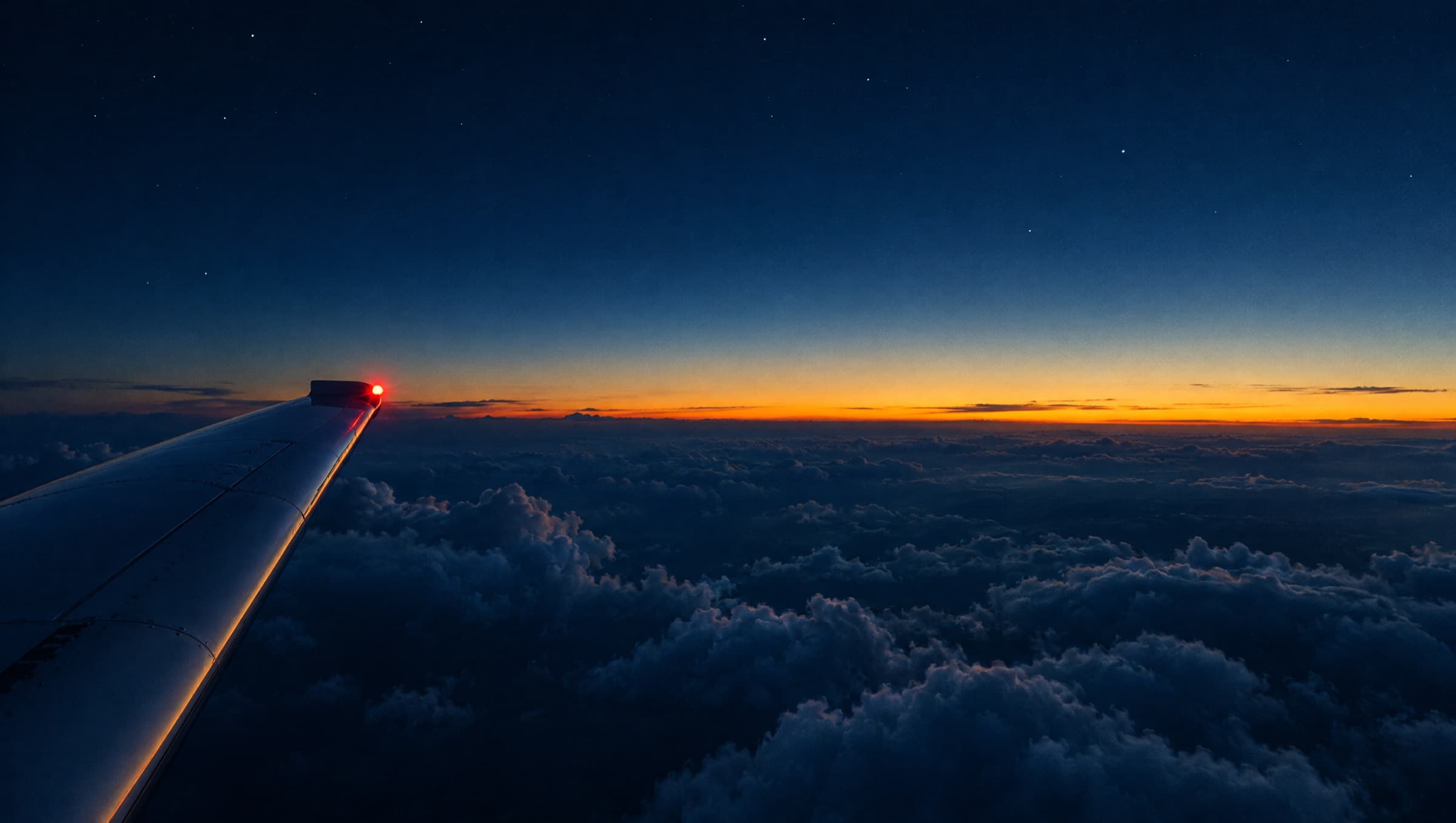 Tragfläche mit roter Positionsleuchte über den Wolken in der Dämmerung. (KI-generiertes Bild)